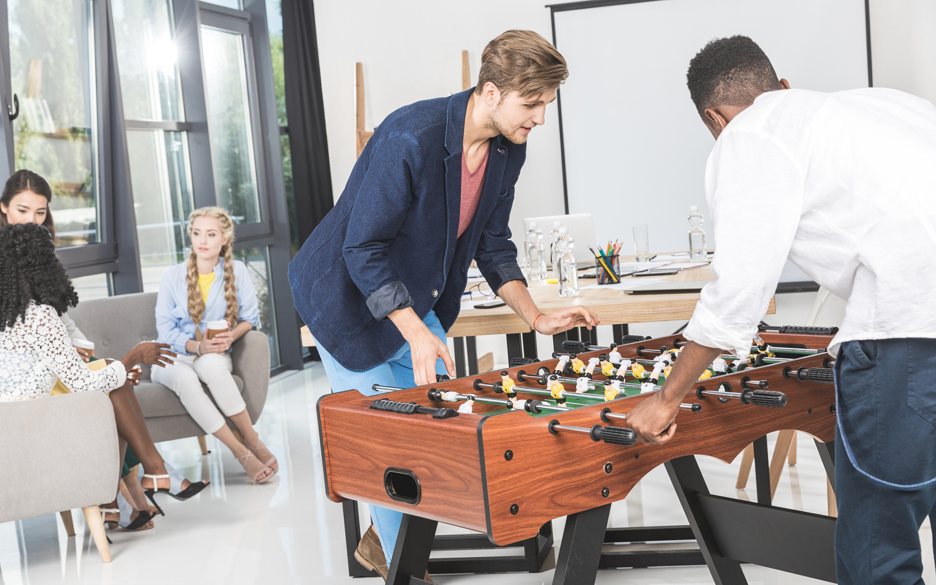 Colleagues playing Foosball together in a break room.