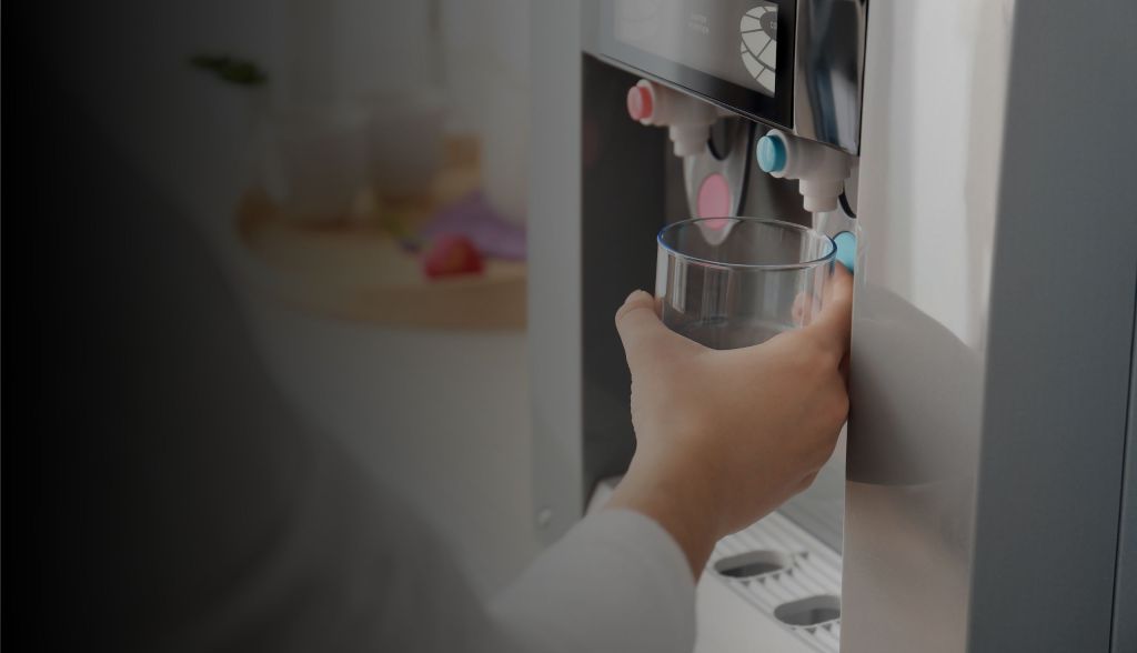 Person filling a glass cup from a water cooler