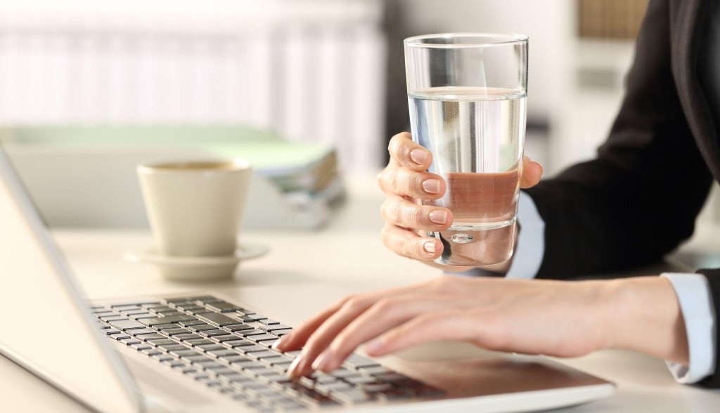 person working on laptop with drinking water