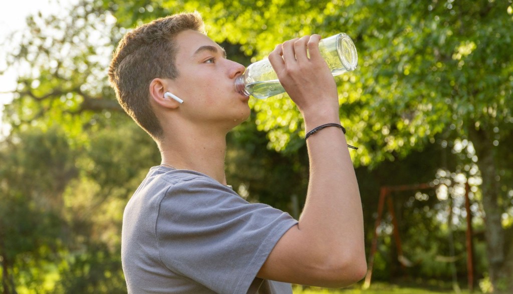 Teenager drinking water from bottle outside