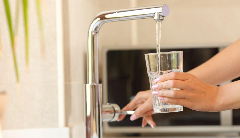 person getting water from faucet