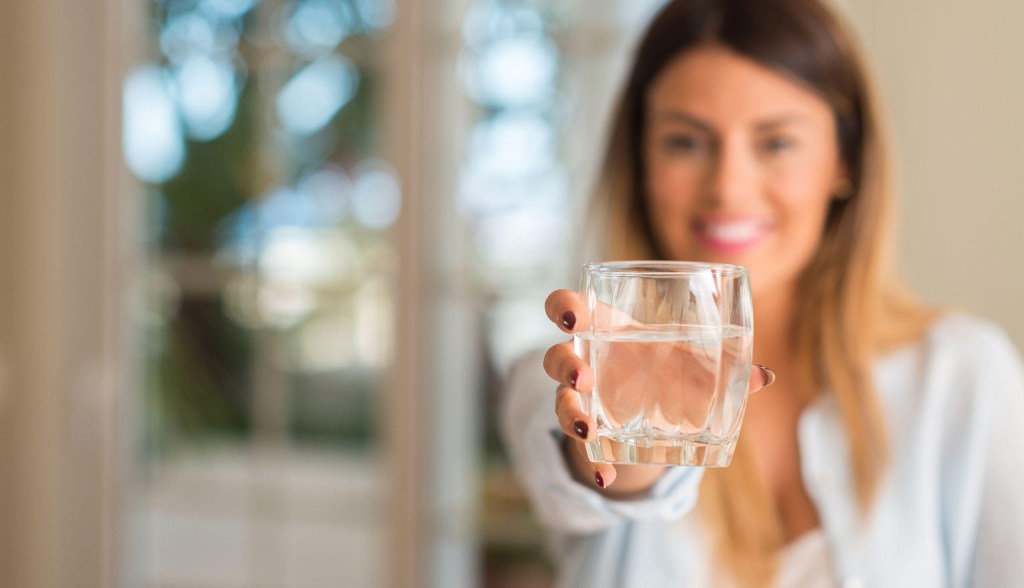 woman holding glass of water smiling