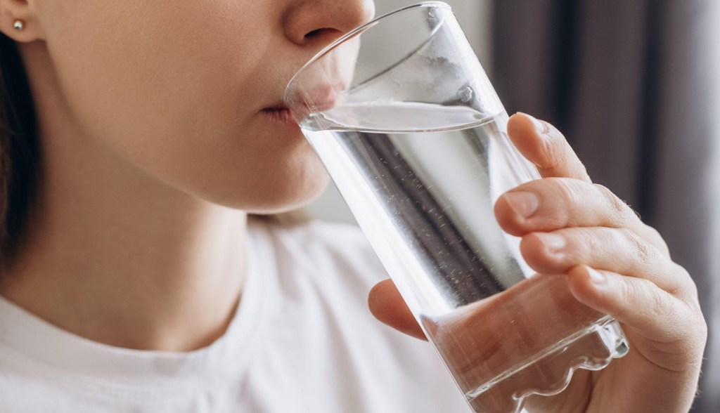 person drinking water from glass