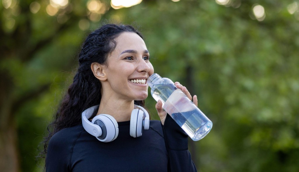 woman drinking from reusable water botlte