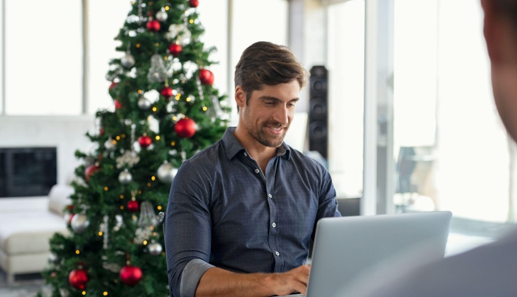 man working with christmas tree in background