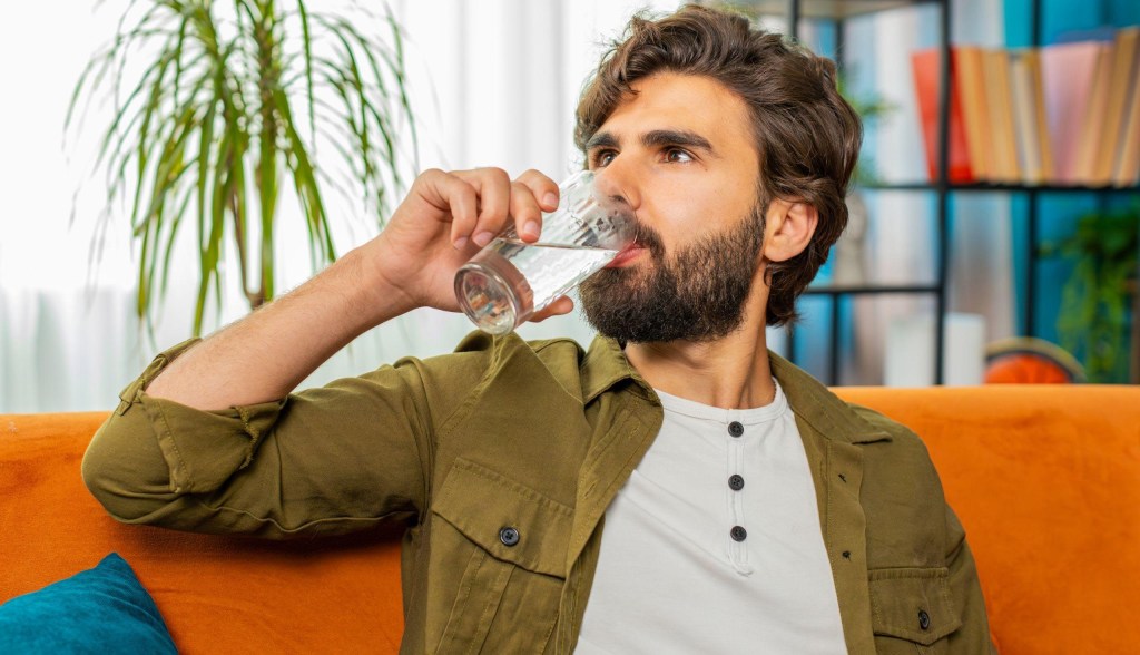 man drinking water on couch