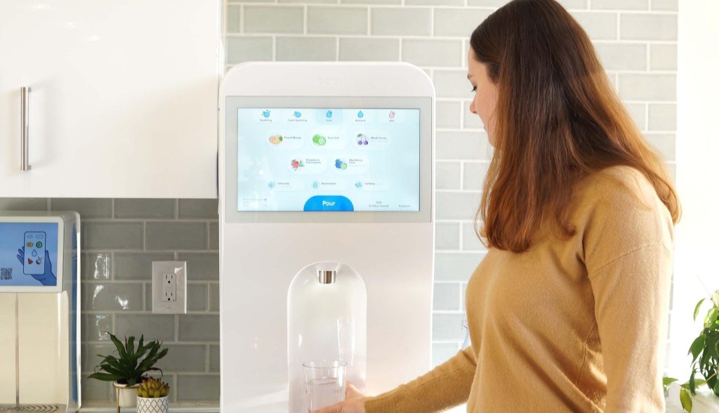 woman using sparkling water dispenser in breakroom