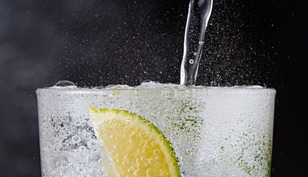 sparkling water into glass with lime