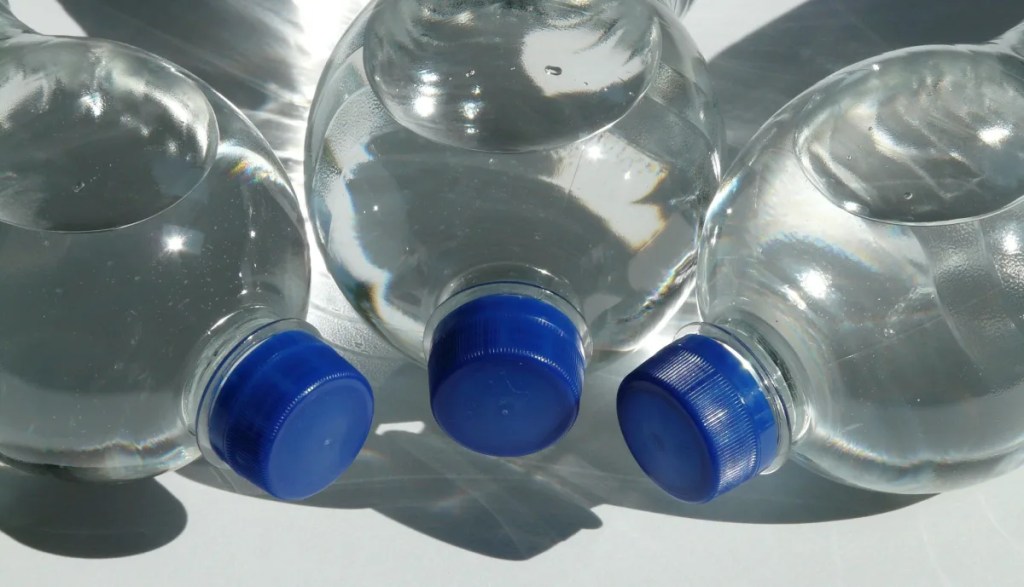 Three water bottles with blue tops lined up on their side