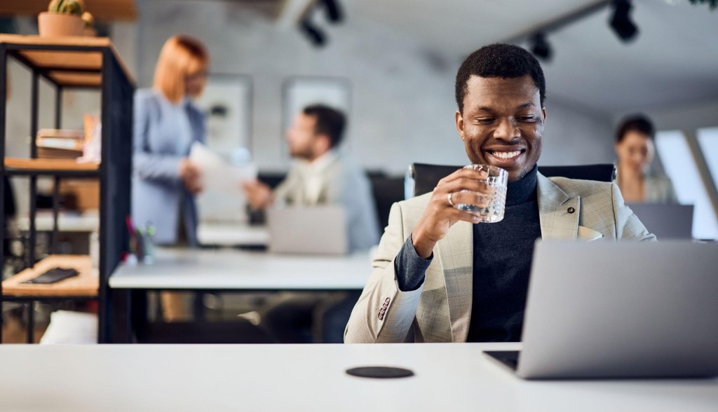 professional man smiling working and drinking glass of water