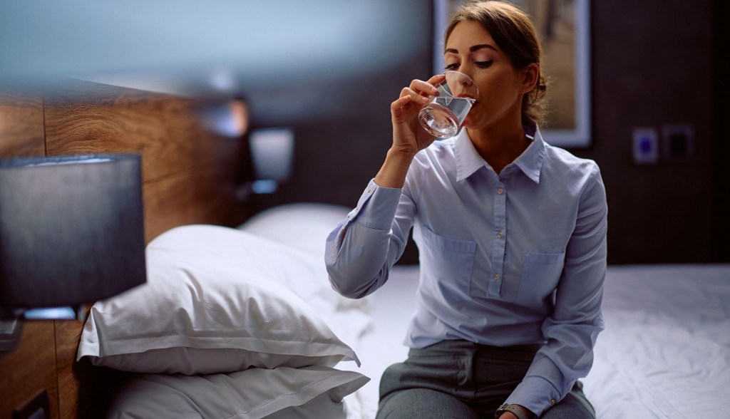 woman drinking water in hotel room