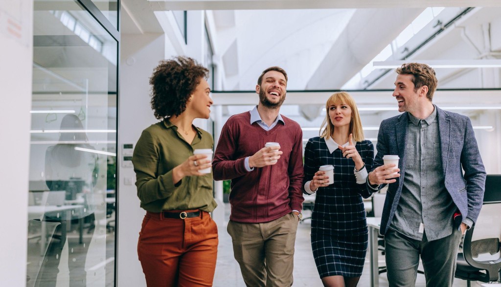 employees standing around talking while holding coffee