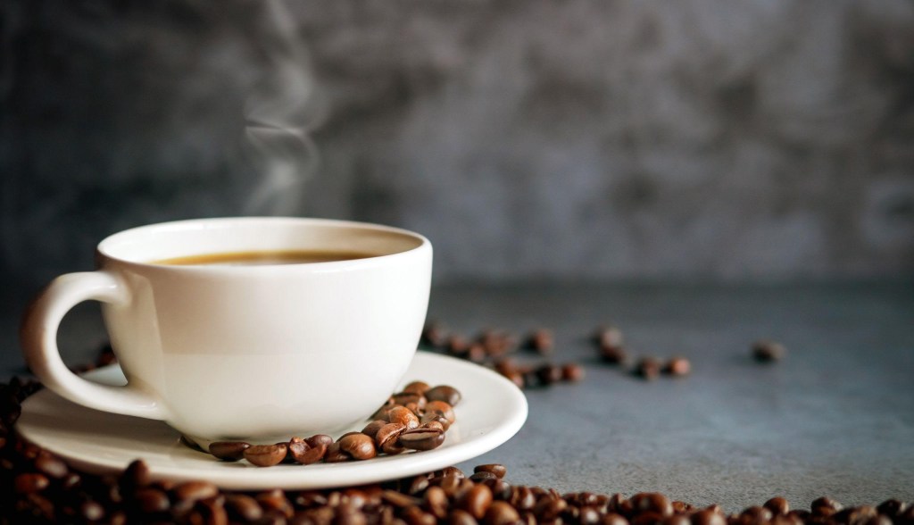 hot cup of coffee with coffee beans