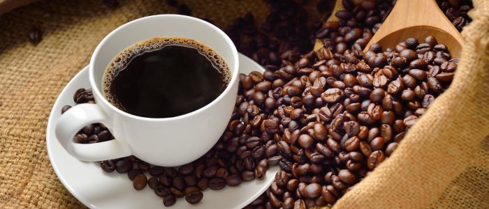 coffee beans next to coffee cup filled with coffee