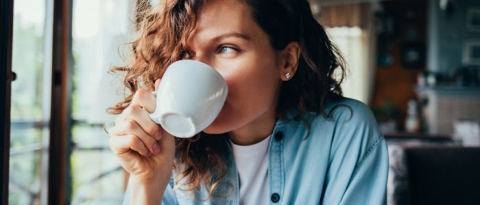 woman drinking coffee and staring out window