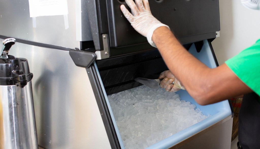 person scooping ice from commercial ice machine