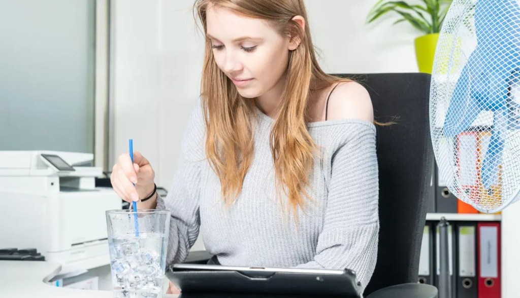 woman working at desk with ice water