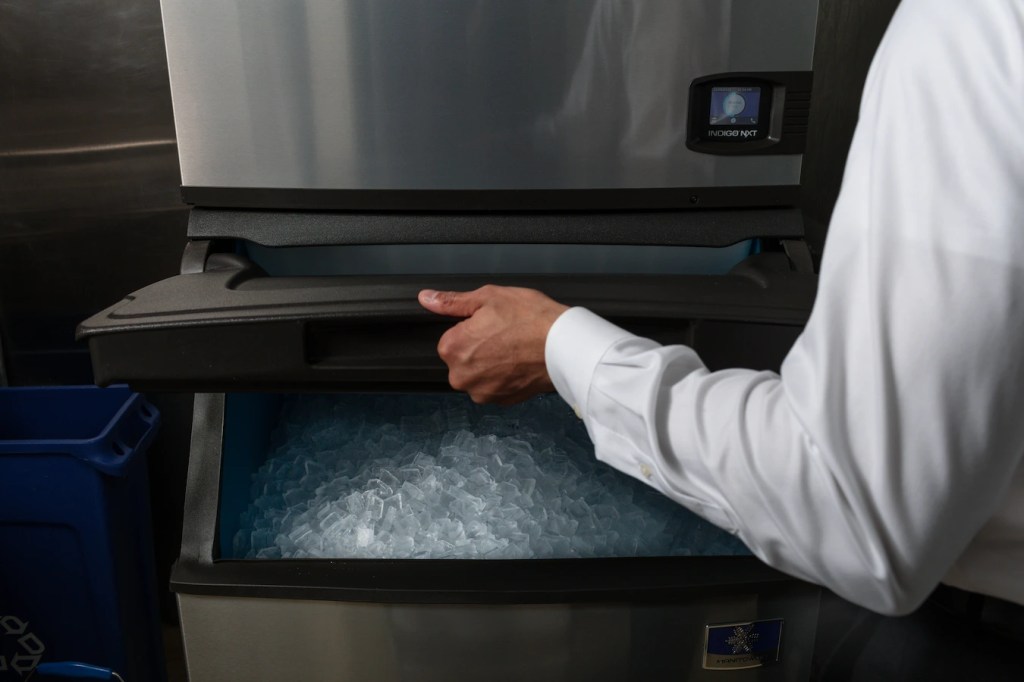 Person lifting up an bin ice machine with one hand