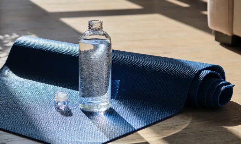 Reusable water bottle at gym with yoga mat