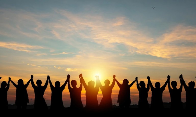 employees all holding hands during sunset