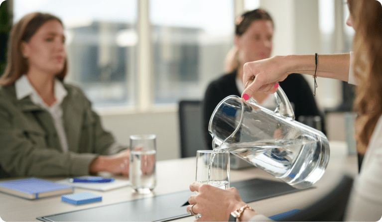 a woman pouring a glass of water from a pitcher