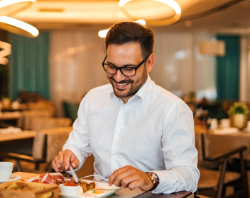 Smiling man with glasses eating food at restaurant