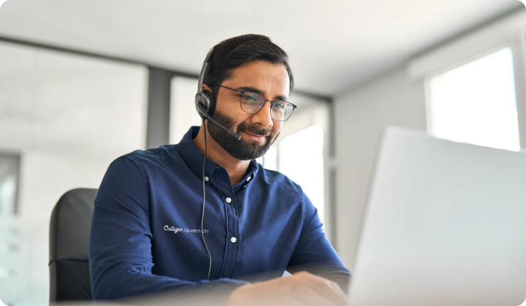 man seated at computer with headset copy