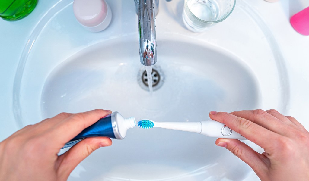 squeezing toothpaste over white sink