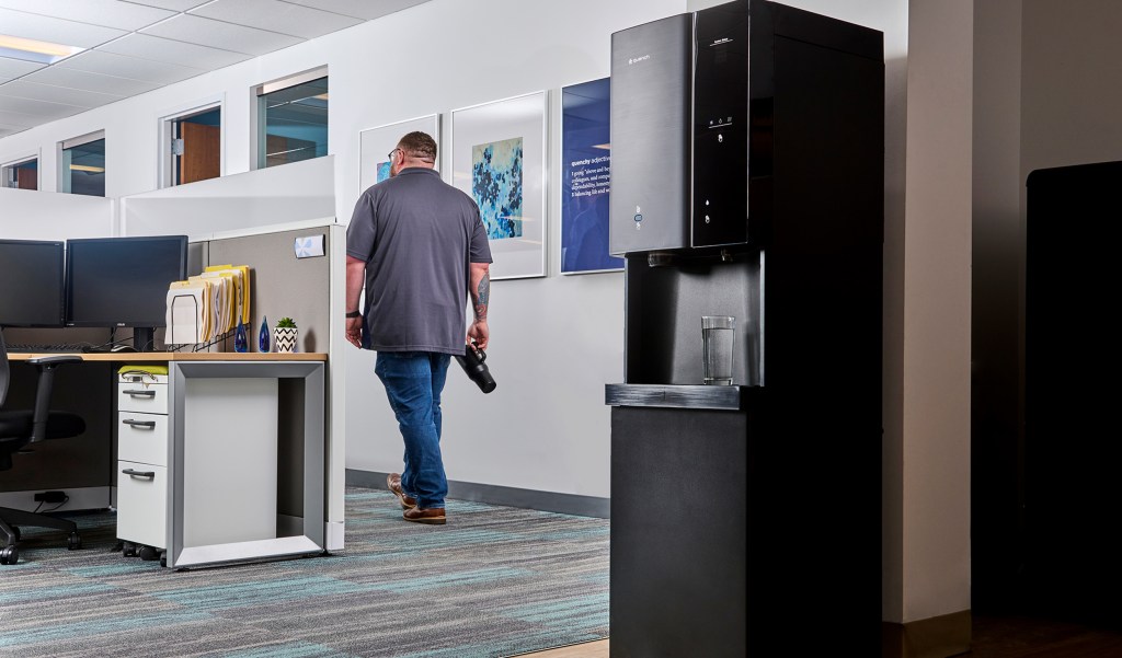 Man in office walking away from a water cooler