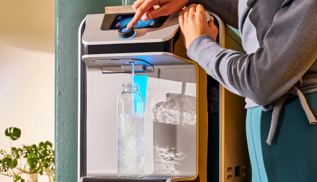 woman in yoga pants and gray sweater dispensing water from bottleless water cooler