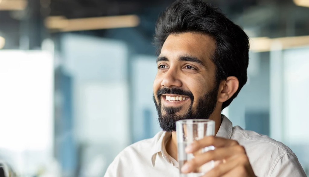 indian man drinking water in an office setting