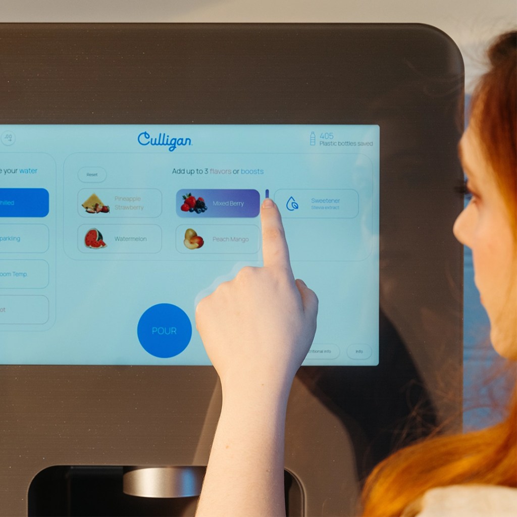 Side shot of woman dispensing water from flavored water dispenser