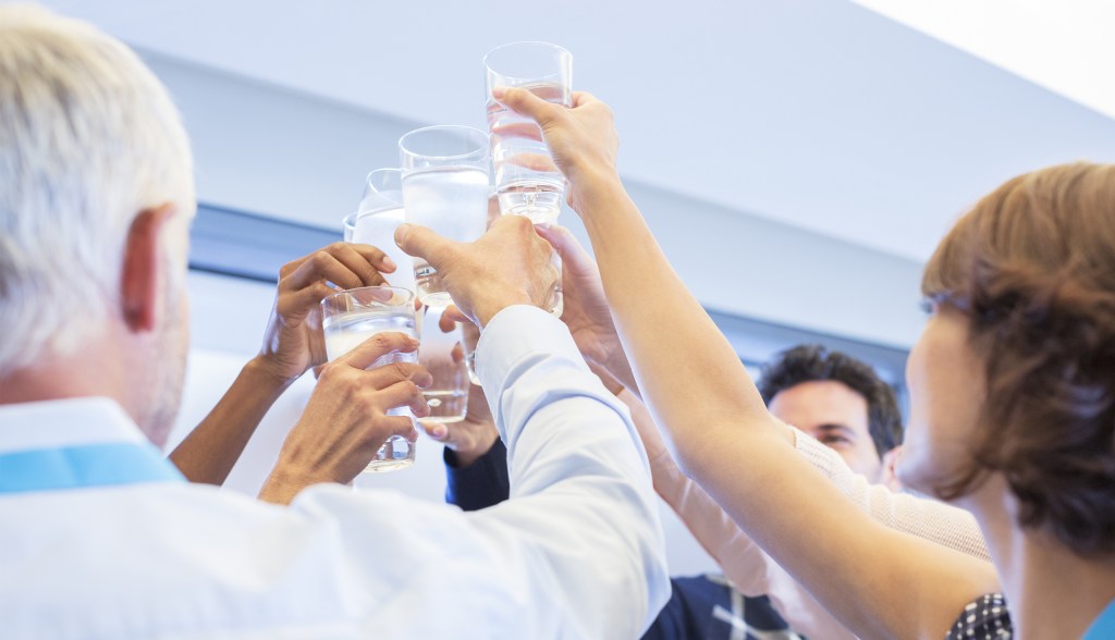 co-workers cheersing withing glasses of water