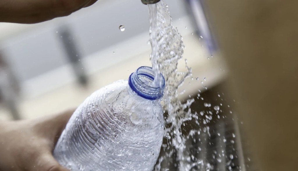 Dispensing water from a faucet into a plastic water bottle