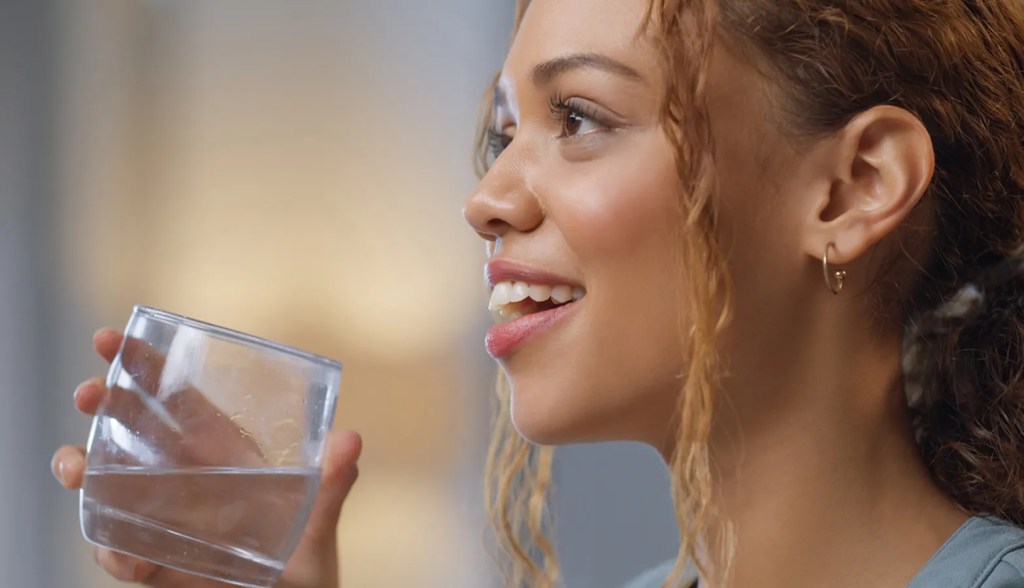 Woman smiling looking up and drinking water