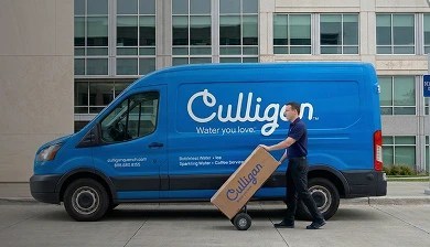 Man rolling out a cardboard box in front of a Culligan service van