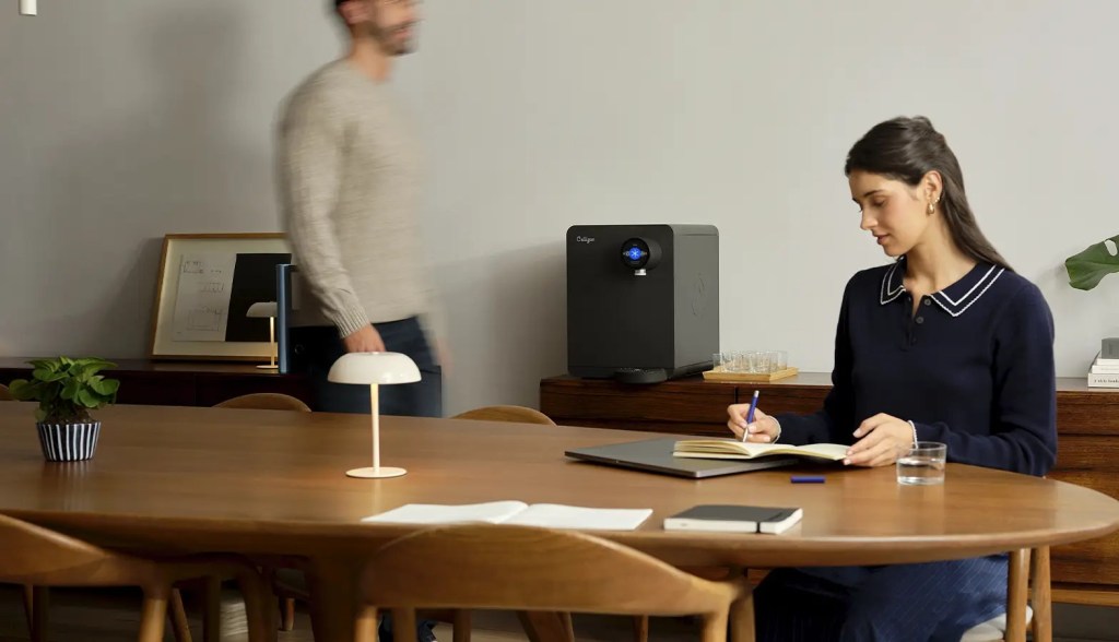 woman working in an office with a countertop machine behind her